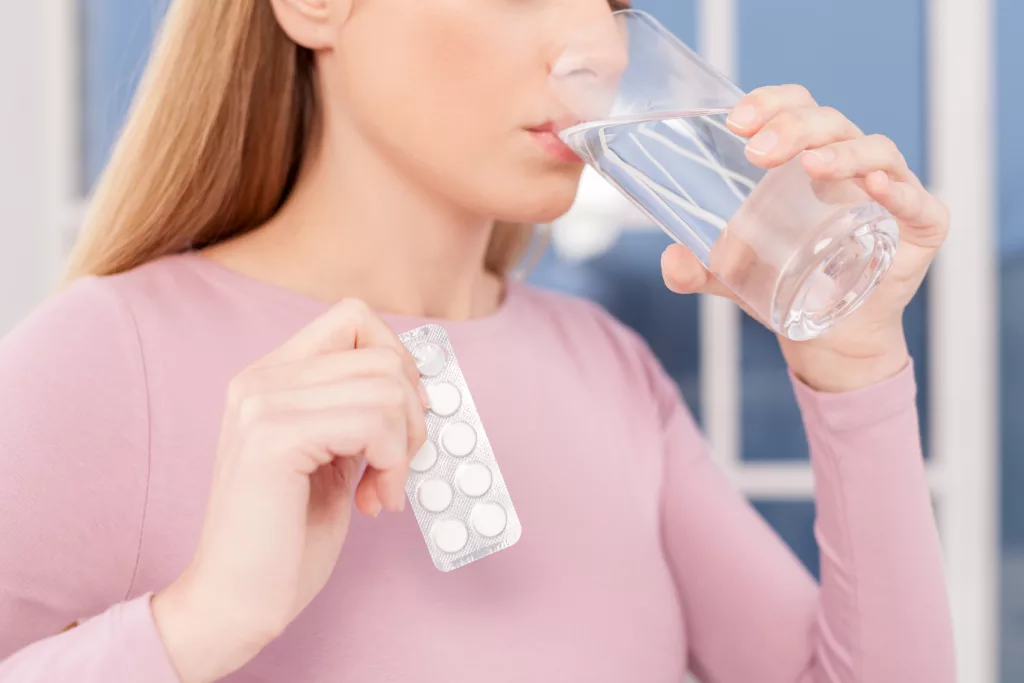 mulher tomando agua e remédio para curar a Zyka