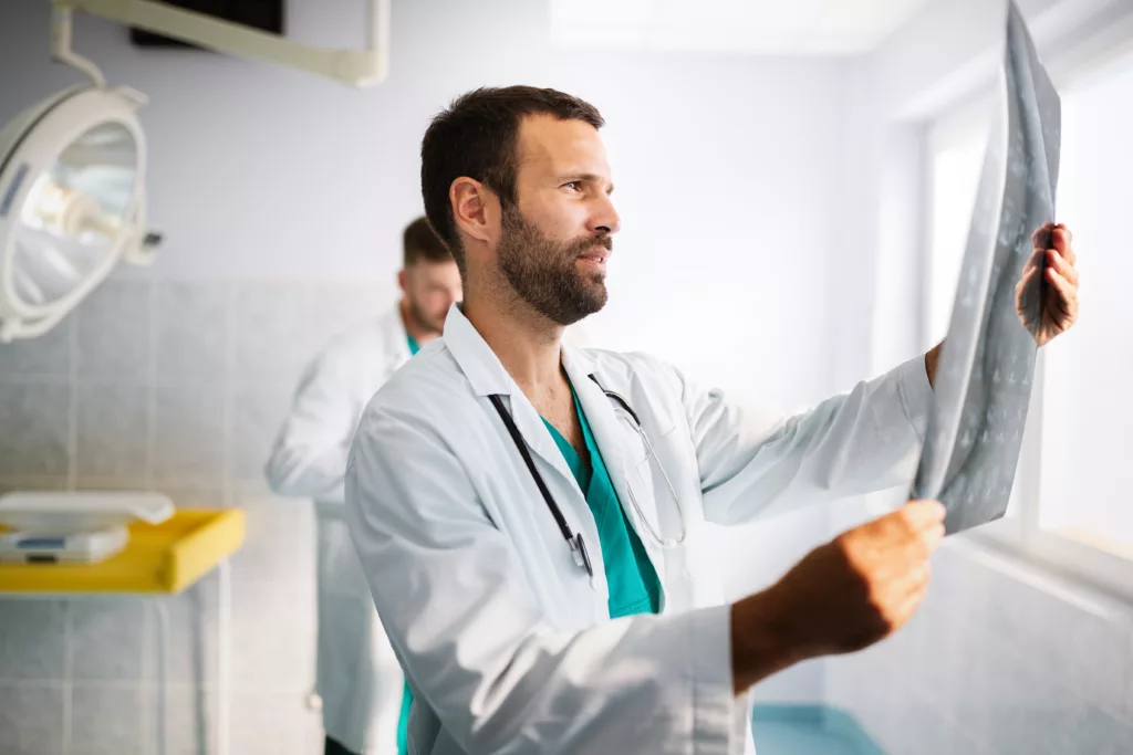 Médico olhando meio indeciso para um raio x pois não achou o diagnóstico ainda