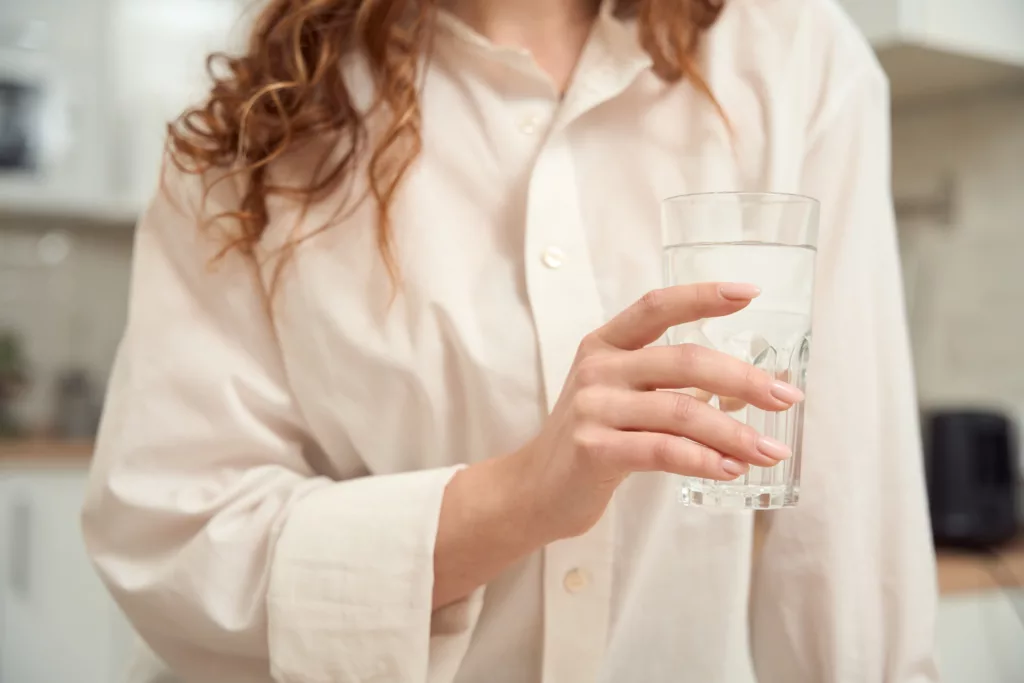 uma mulher se recuperando da dengue, tomando bastante liquido
